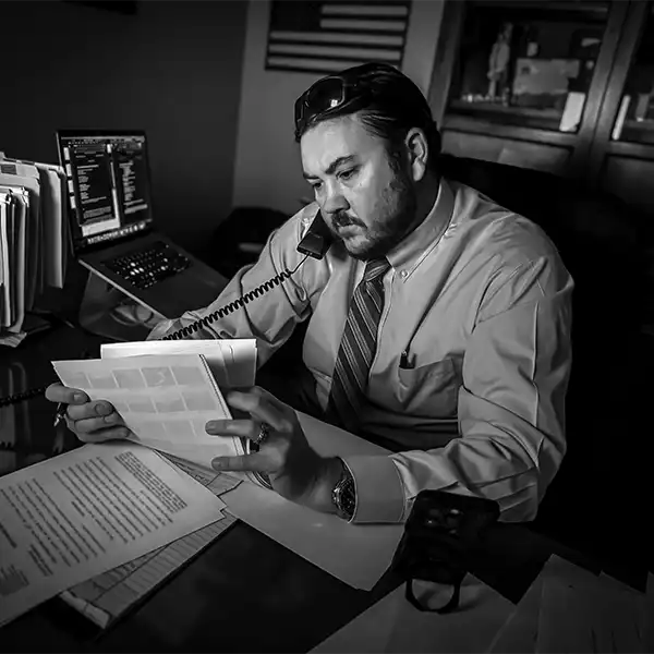 Attorney William M. Shingler Jr. at his desk reviewing case documents and speaking on the phone<br />
